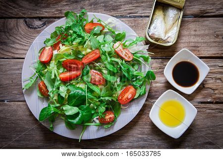 fresh mix of lettuce salad with tomato and a can of sardines in olive oil