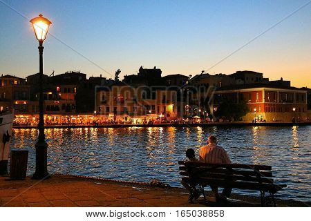 Sunset view of a grandfather tellking stories to his nephew in front of  Xania's harbour, Crete, Greece.
This suggestive place is also called the Little Venice