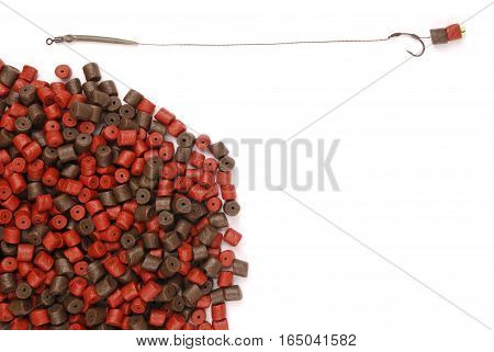 Fishing bait with hook and brown with red pre-drilled halibut pellets for carp fishing isolated on white background with soft shadow