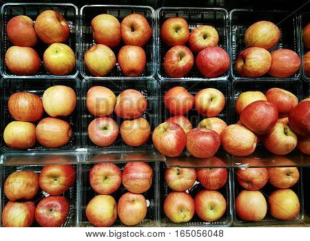 Full frame rows of red apples grouped and stacked on display shelves for sale