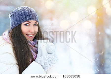 Winter young woman portrait. Beauty Joyful Model Girl holding thermocup and smiling, having fun in winter park. Beautiful young woman laughing outdoors. Enjoying nature, wintertime.