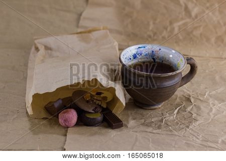 cup of tea near the paper bag with sweets on crumpled paper. tea and sweets