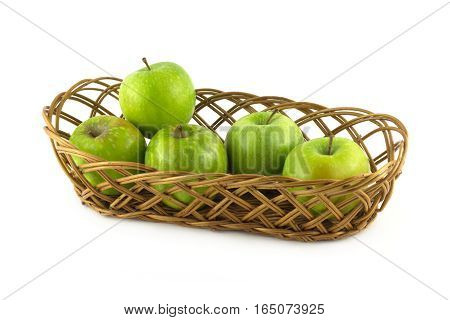 Five ripe green apples in long brown wicker basket isolated on white closeup