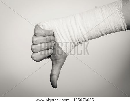Bad news and information. Medicine aspects. Male hand with bandage showing thumb down sign symbol.