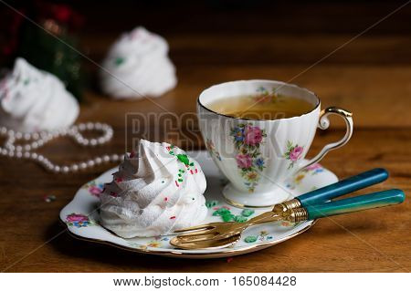 refined porcelain cup of tea and sauser with zephyr meringue marshmallow vintage fork and spoon wood pearls