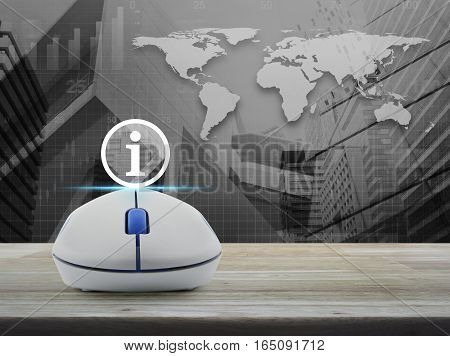 Wireless computer mouse with information sign icon on wooden table over world map with financial graph and city tower Elements of this image furnished by NASA