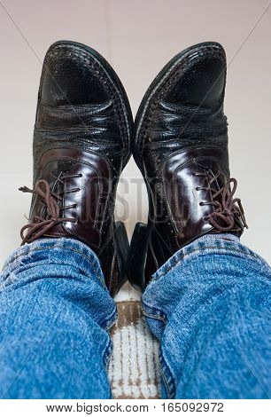Close up men wear blue jean and brown leather shoes on floor.