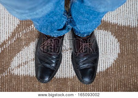 Close up men wear blue jean and brown leather shoes on floor.