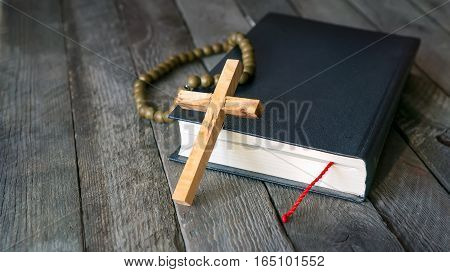 Wooden cross, Holy Bible and vintage rosary beads.