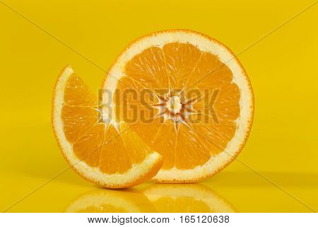 Studio shot of a cross section and a slice of an orange fruit isolated on yellow background. All in focus using focus stacking technique. Focus stacked image