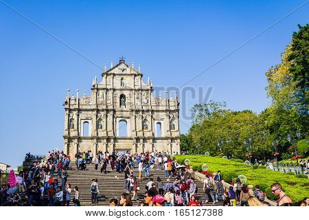 Macao China - December 9 2016: Tourists and local residents walk pass and take photos at The Ruins of St. Paul's in sunny day crowded tourist in blue sky sunny day