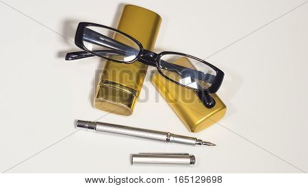 The glasses, gold case and a pen. Isolate white background.