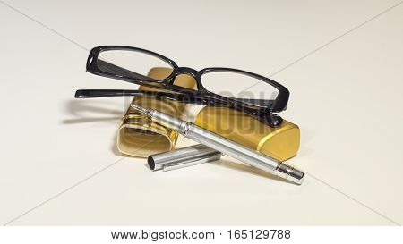 An elegant black glasses, case, metal pen on the white isolate background.