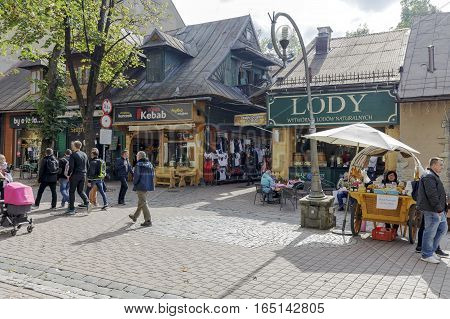 ZAKOPANE POLAND - SEPTEMBER 23 2016: Several people walk at Krupowki street along different shops and cafes operating by the same street