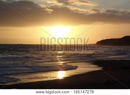 The sun breaks out of the clouds just in time for a beautiful sunset over the ocean.