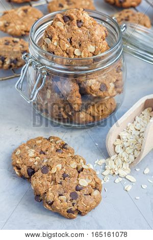 Flourless gluten free peanut butter oatmeal and chocolate chips cookies in glass jar and on table vertical