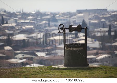 retro old well on the background of the city panorama. Kutaisi Georgia.