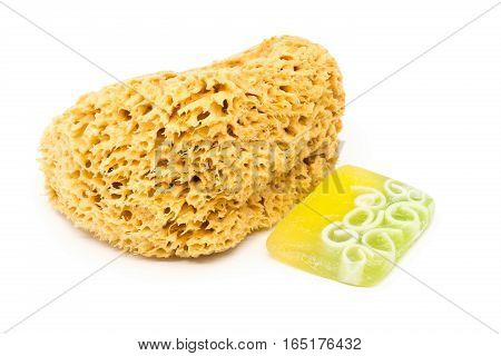 Natural yellow cleaning sponge with handmade soap bar over white background