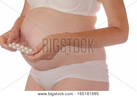 Pregnant in light lingerie holding a pill in hand