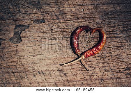 Two Chili Peppers Forming A Shape Of Heart On Old Wooden Background. Love Valentine Concept.