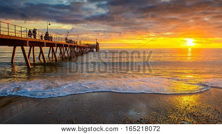 People walking along Glenelg Beach jetty at sunset South Australia