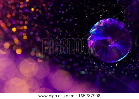 Glitter and glow soft multi colored bokeh shining with big natural jewelry precious stone. Dark abstract dreamy wunderful sparkle background