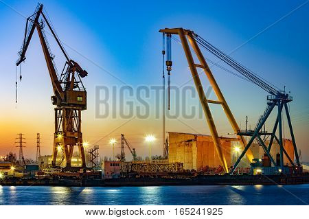 Floating crane at night in port .