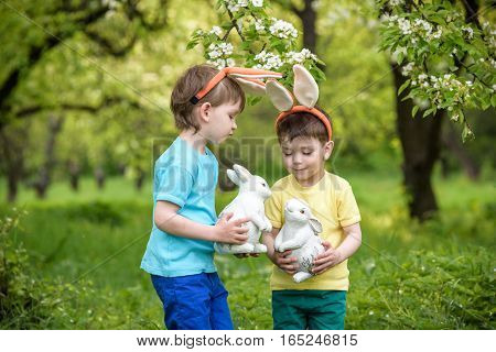 Two Little Kids Boys And Friends In Easter Bunny Ears During Traditional Egg Hunt In Spring Garden,