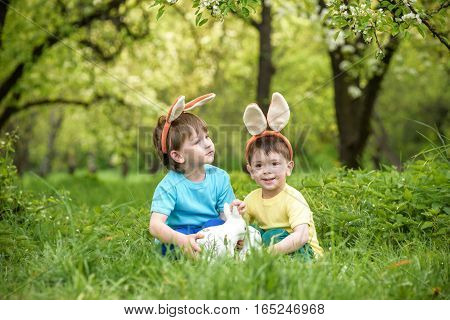 Two Little Kids Boys And Friends In Easter Bunny Ears During Traditional Egg Hunt In Spring Garden,