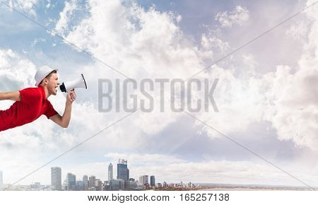 Young man in hat making announcement in megaphone