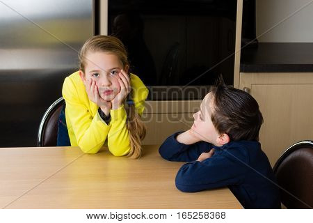 Kids (siblings boy and girl) are arguing at the kitchen table