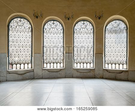 Windows with iron decorated grid, yellow wall, and marble floor
