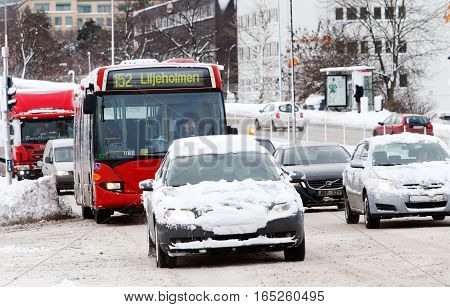 Solna Sweden - January 4 2017: Snowy vehicles with hidden license plates on street Frosundaleden towards Solna city center at the junction with the street Ankdammsgatan.