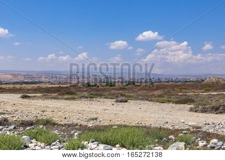 Landscape view of Lady's Mile in Limassol, Cyprus.  Taken in the summer and shows dried up lake bed with misty urban view and mountains in the background.