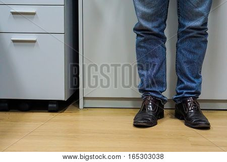 Close up men wear blue jean and brown leather shoes on floor.