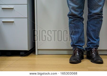 Close up men wear blue jean and brown leather shoes on floor.