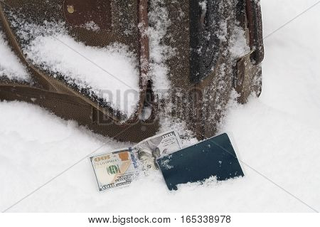 Lost abandoned luggagge covered with ice and snow with passport and cash in the foreground
