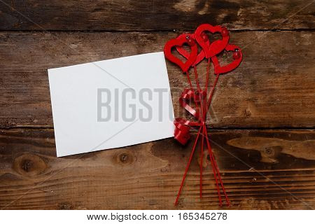 Red hearts and paper on the wooden board