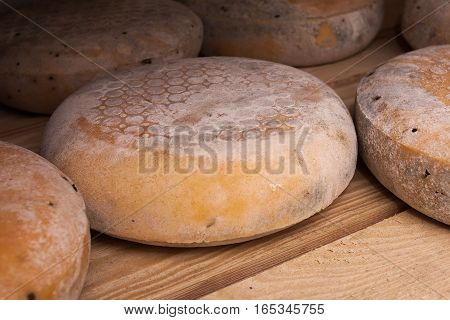 A cheese on a wooden shelves in a factory