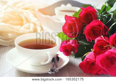 Valentine's Day: Romantic morning Tea Party for two with burning candles and bouquet of red roses. Toned image