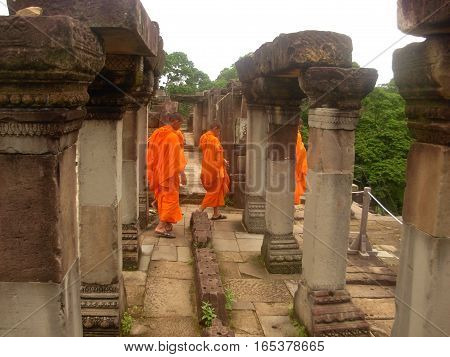 SIEM REAP, CAMBODIA - AUGUST 06, 2014 - Unidentified young buddhist monks walking inside the ruins of Baphuon temple