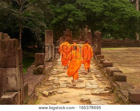 SIEM REAP, CAMBODIA - AUGUST 06, 2014 - Unidentified young buddhist monks walking inside the ruins of Baphuon temple