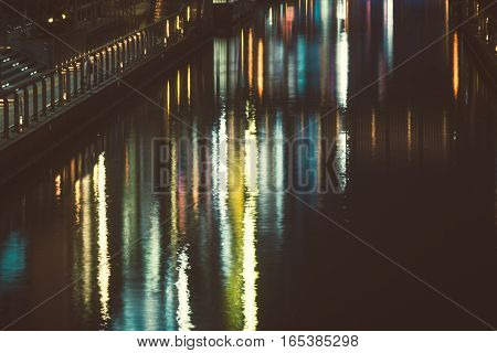 the reflection of light waves in the water Colored city lights reflected on water surface in night.