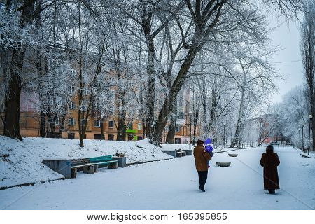 Winter alley city park a man carries a small child in her arms