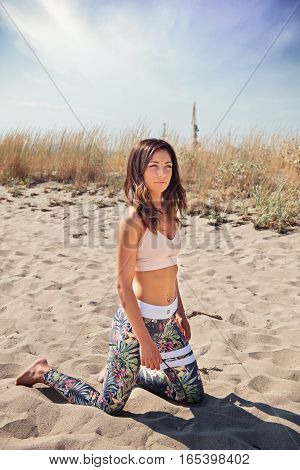 Active young woman streching and doing exercise on the beach.