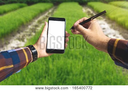 Hand holding blank smart phone and pen for Ecology Farming Agriculture business Environment Concept