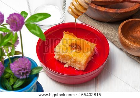 Basbousa - arabian cake with almonds and honey syrup in red bowl on white wooden background