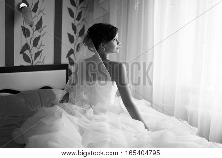 Portrait of beautiful bride with fashion veil posing at home at wedding morning. Makeup. Blondegirl with elegant hair styling. Wedding dress.