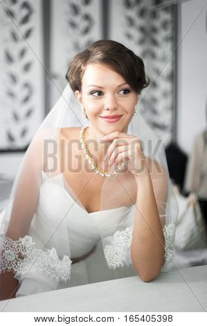 Portrait of beautiful bride with fashion veil posing at home at wedding morning. Makeup. Blondegirl with elegant hair styling. Wedding dress.