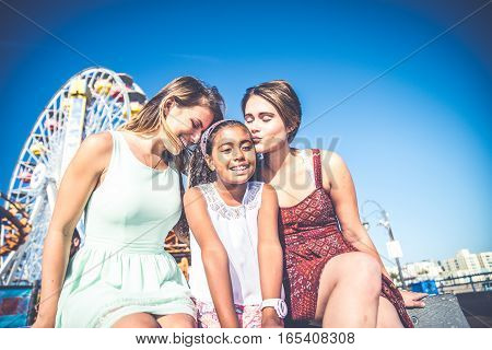 Lesbians mothers with adopted child - Happy homosexual family playing with her daughter